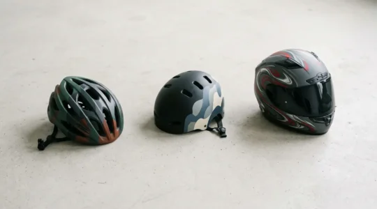 Casques de protection pour vélo, trottinette électrique et moto posés sur un fond neutre minimaliste